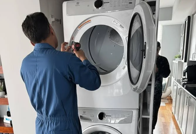 Technician inspecting a stacked front-loading laundry appliance