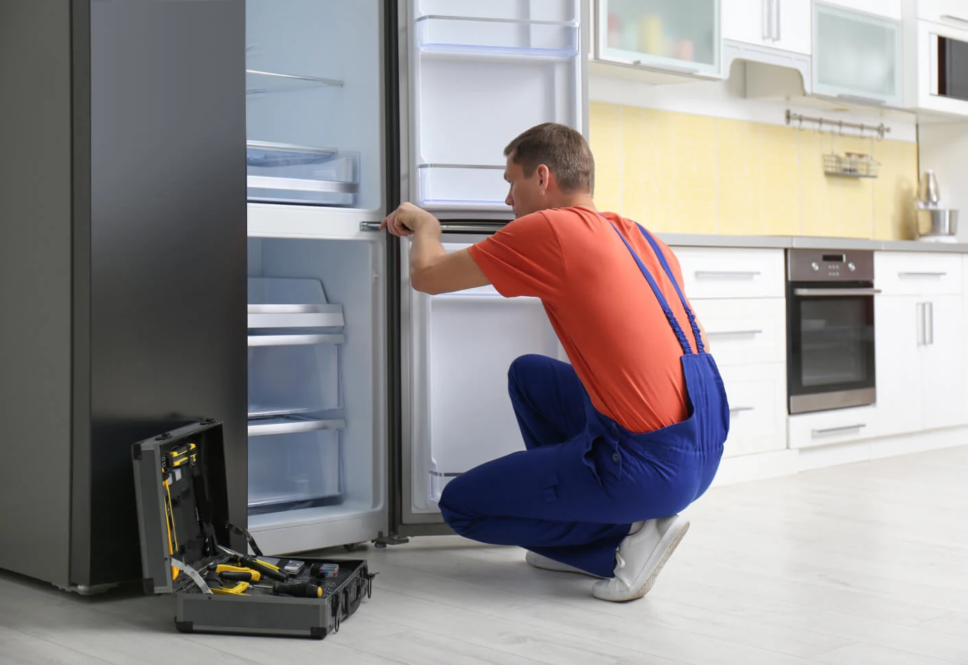 Repair professional inspecting a refrigerator in a residential kitchen